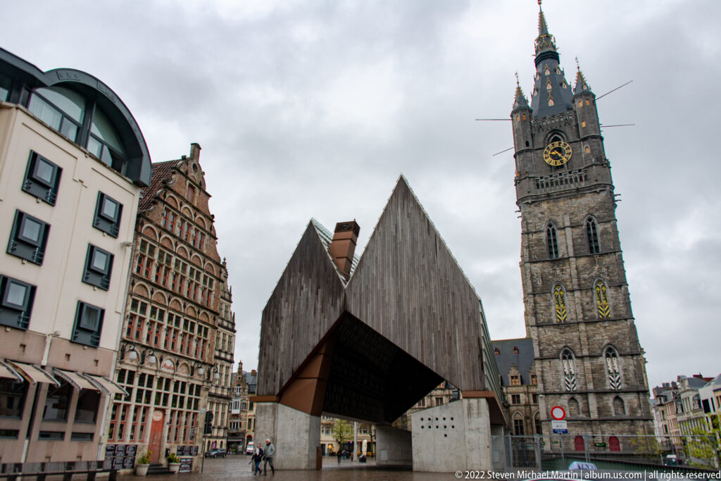 Ghent City Pavilion in front of the tall stone Belfry, with historic stepped-gable buildings to the left.
