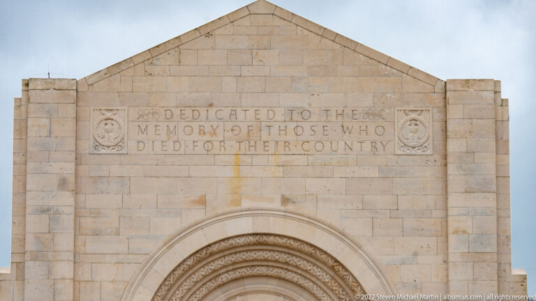 Carved chapel dedication above an arched entrance reads, 'Dedicated to the memory of those who died for their country.'