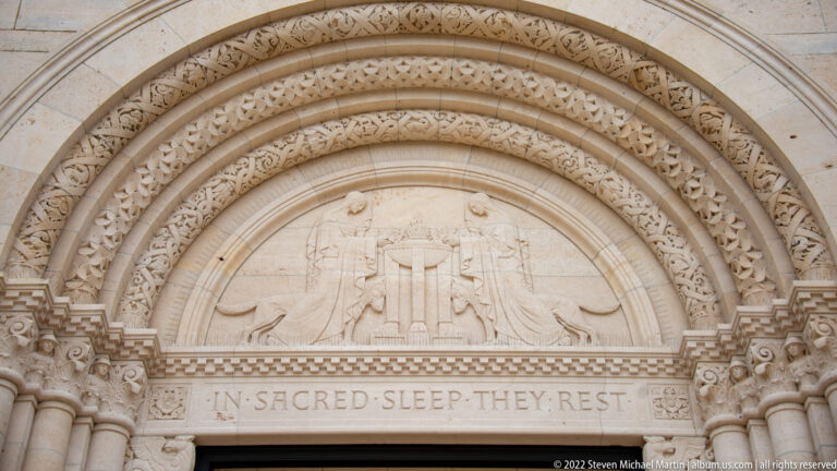 Carved chapel tympanum with kneeling figures above the inscription 'IN SACRED SLEEP THEY REST.'