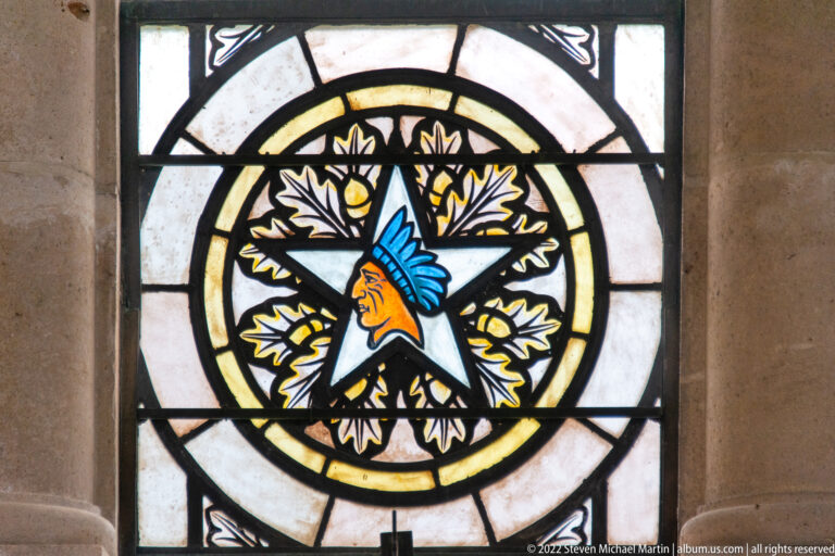 Stained-glass medallion with a Native American profile in a blue headdress centered inside a star.