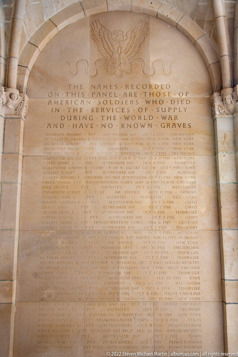 Arched stone memorial panel headed by an eagle and inscription above dense columns of names.