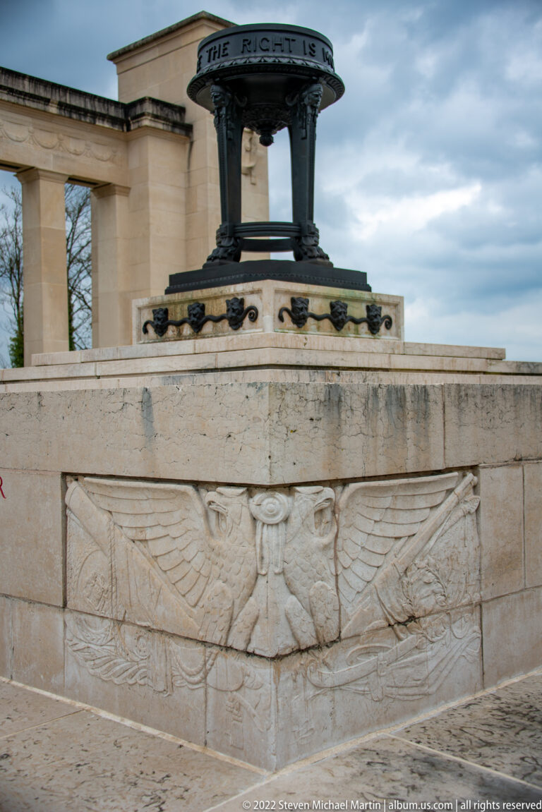 Spread-wing eagle relief carved into the stone base below a dark bronze memorial canopy.