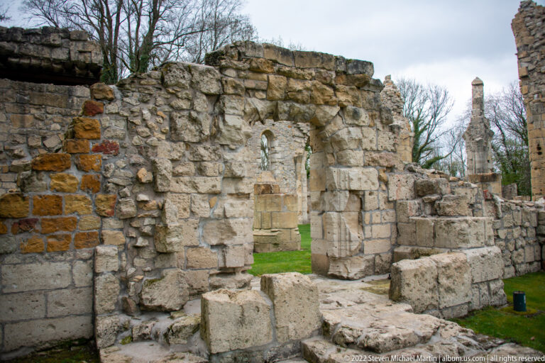 Close view of broken stone walls with a small opening, rubble masonry, and missing upper sections.