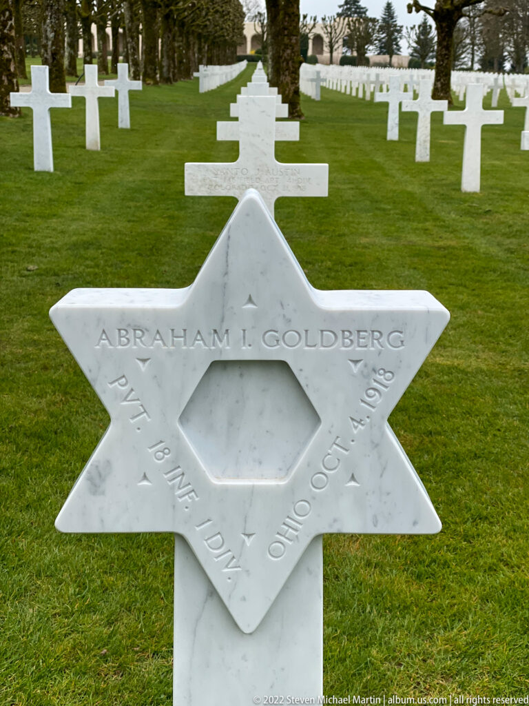 White Star of David headstone for Abraham I. Goldberg stands before rows of Christian crosses.
