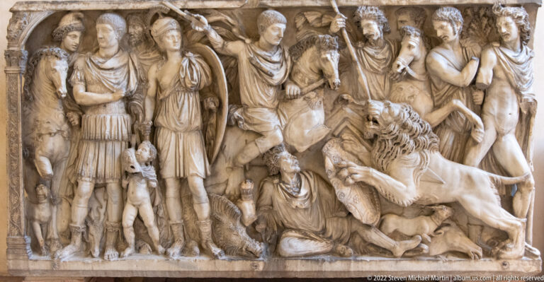 Classical stone relief crowded with armored figures, women, horses, and a dynamic battle scene.