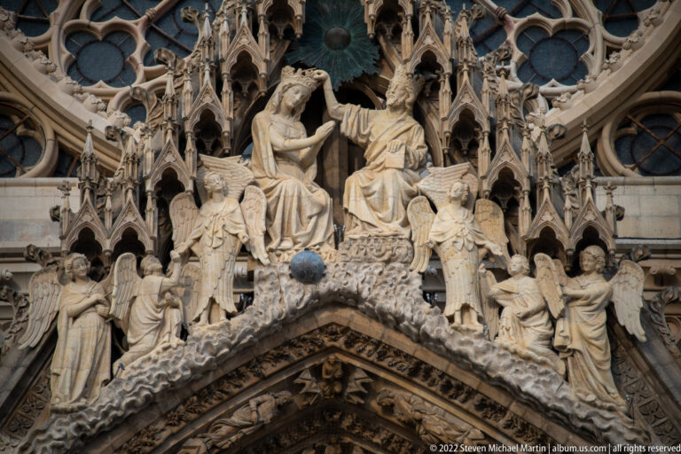 Christ crowns the Virgin in a Gothic sculptural group surrounded by angels above a Reims Cathedral portal.