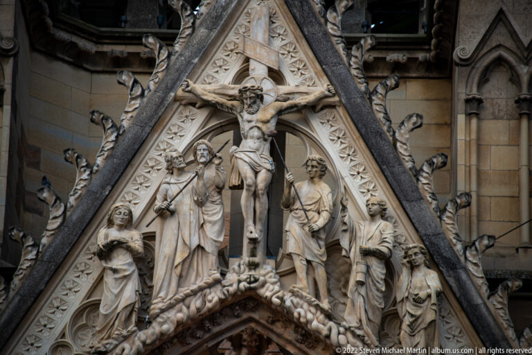 Crucified Christ with mourners and attendants arranged within a steep triangular Gothic gable.