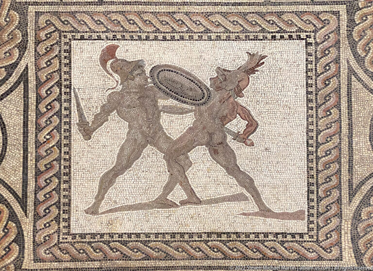 Mosaic of two nearly nude male combatants, one holding an oval shield, within geometric borders.