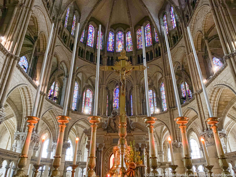 Choir and apse of Saint-Remi with gilded candlesticks, clustered columns, rib vaults, and tall stained glass.
