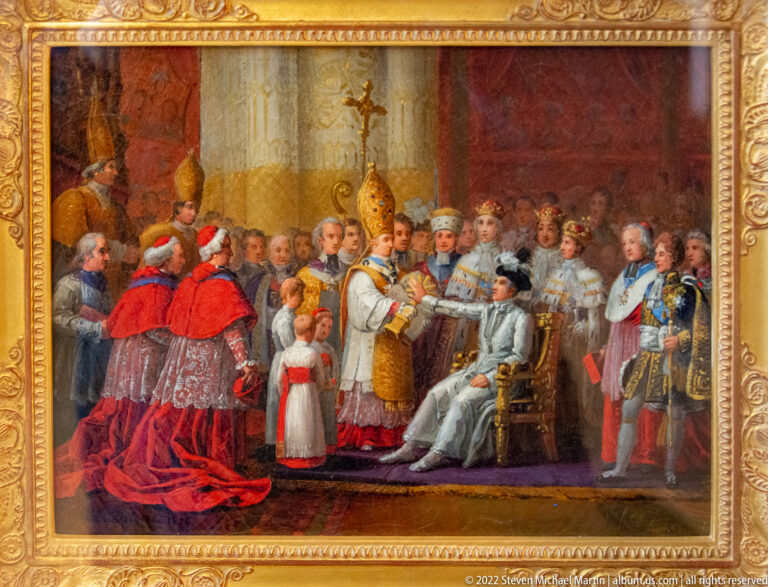 Clergy and courtiers surround a seated ruler during a formal church ceremony with mitres and red vestments.
