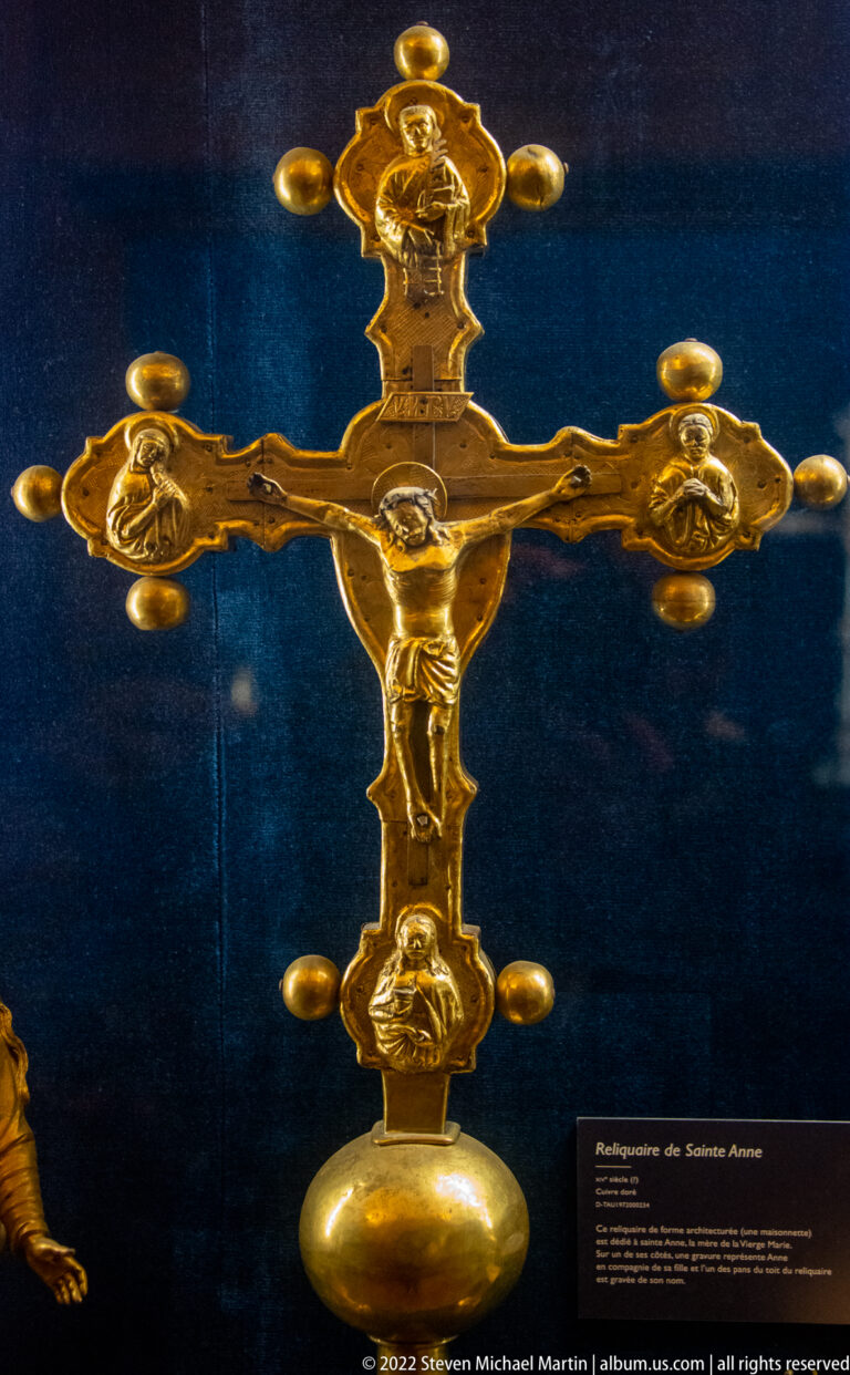 Gold crucifix with small corpus of Christ, lobed terminals, and relief medallions at the arm ends.
