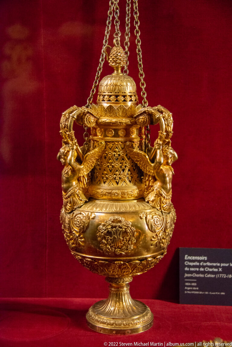 Gilt hanging censer with chains, pierced upper section, sculptural figures, and ornate floral decoration.