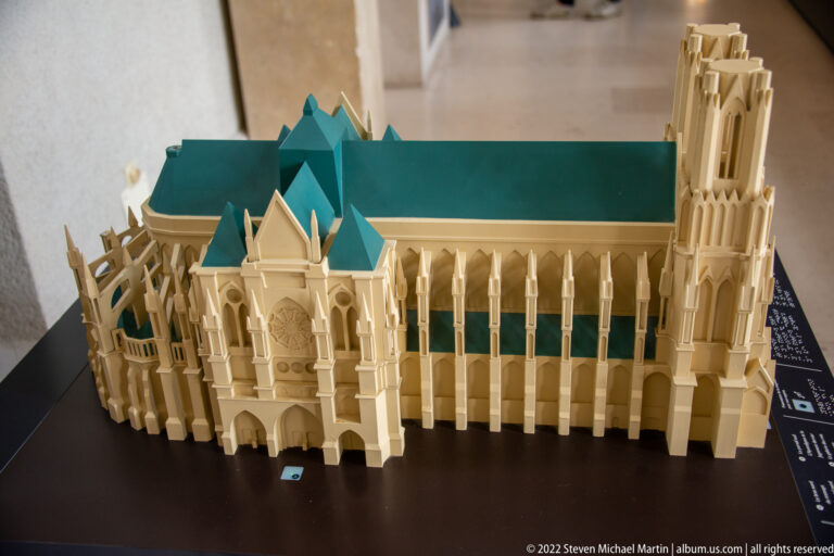 Scale model of Reims Cathedral seen from the apse side, with flying buttresses, long roof, and western towers.