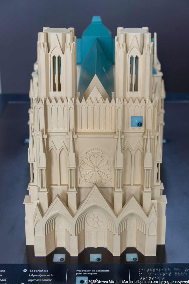 Front view of Reims Cathedral scale model with twin towers, rose window, and three main portals.
