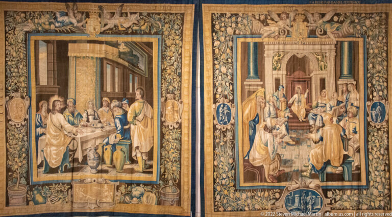Two large figurative tapestries displayed side by side, each filled with figures and elaborate woven borders.