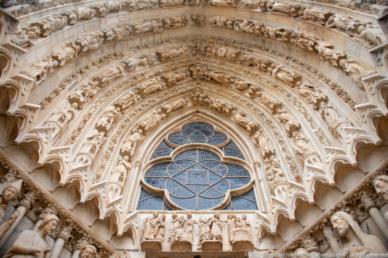 Reims Cathedral portal detail with sculpted archivolts, rows of figures, and a small rose window.