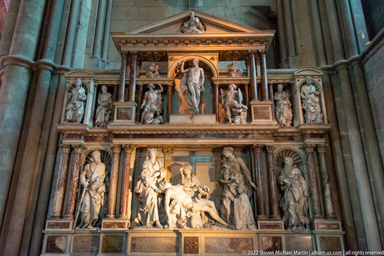 Large Renaissance-style wall tomb with columns, pediments, standing figures, and a crowded central sculptural group.