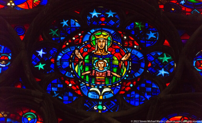 Virgin and Child centered in a brightly colored circular stained-glass design with radiating stars and roundels.