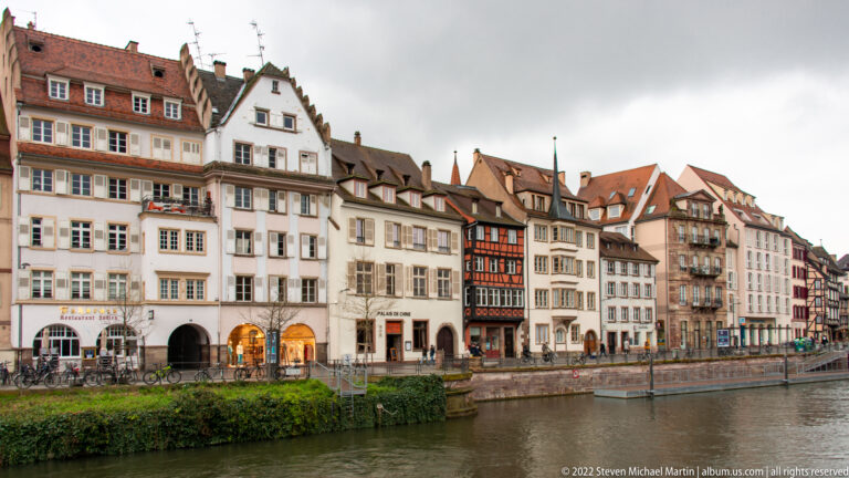 Historic multistory houses with varied roofs and façades line a quay beside the Ill in Strasbourg.