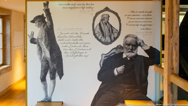 Interpretive panel with historical portraits, handwritten quotations, and a seated bearded man in formal nineteenth-century dress.