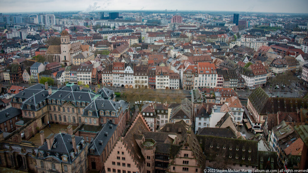 Wide elevated panorama of Strasbourg’s historic center with tiled roofs, monumental buildings, and modern skyline beyond.