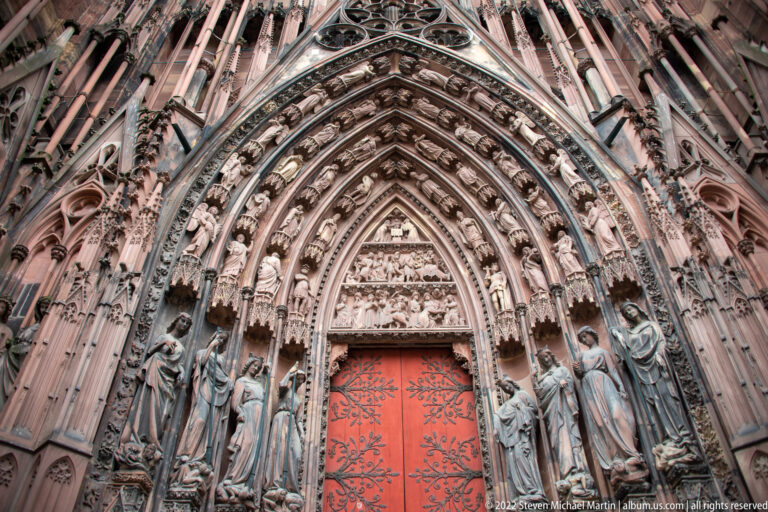 Strasbourg Cathedral portal with red doors, pointed archivolts, standing stone figures, and a densely carved tympanum.