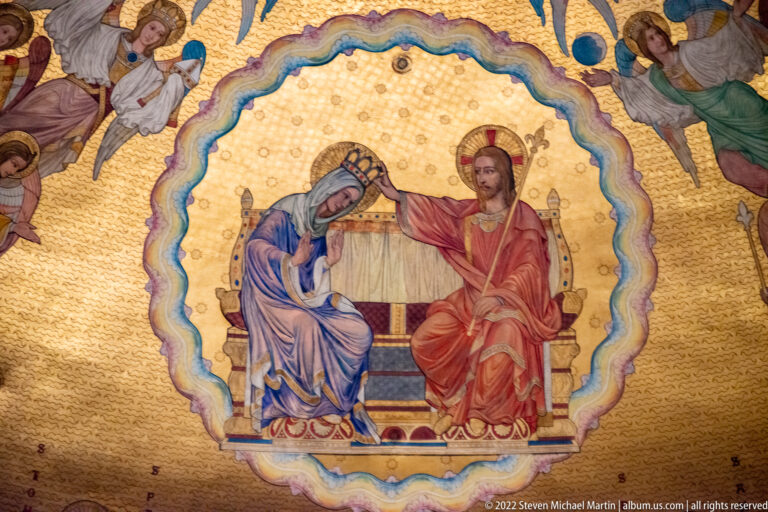 Gold mosaic of Christ crowning the seated Virgin Mary, surrounded by a radiant border and angels in Strasbourg Cathedral.
