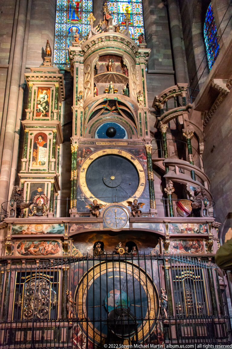 Lower and central sections of Strasbourg Cathedral's astronomical clock with circular display, painted panels, and railings.