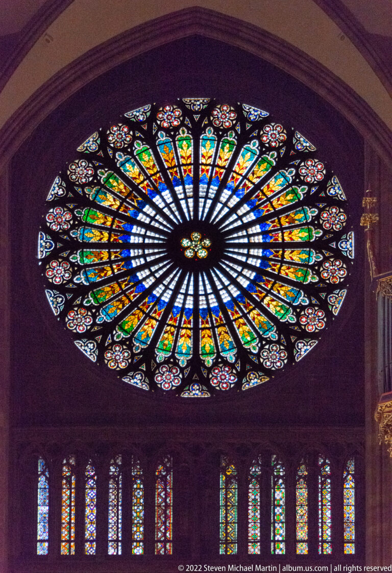 Large circular stained-glass rose window above a row of tall lancet windows in Strasbourg Cathedral.
