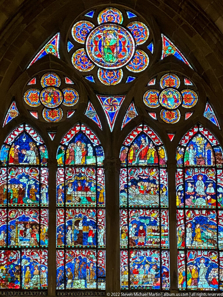 Four densely figured stained-glass lancets topped by circular and triangular tracery lights in Strasbourg Cathedral.