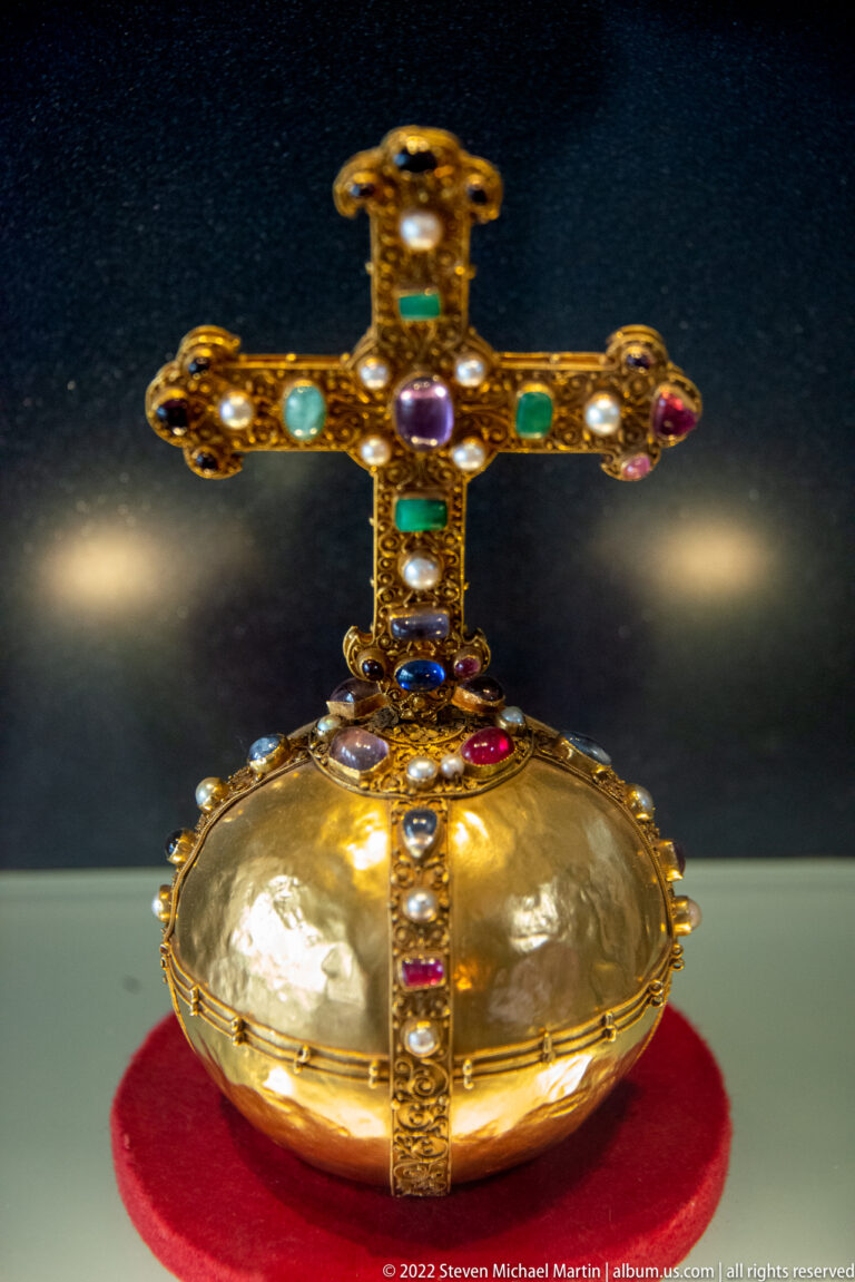 Gold orb-shaped treasury object topped with a jeweled cross and set with colored stones and pearls.