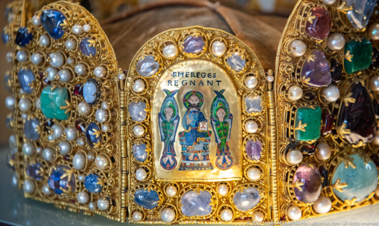 Enamel plaque reading EMERGES REGNANT on a jeweled crown, surrounded by pearls and pale gemstones.