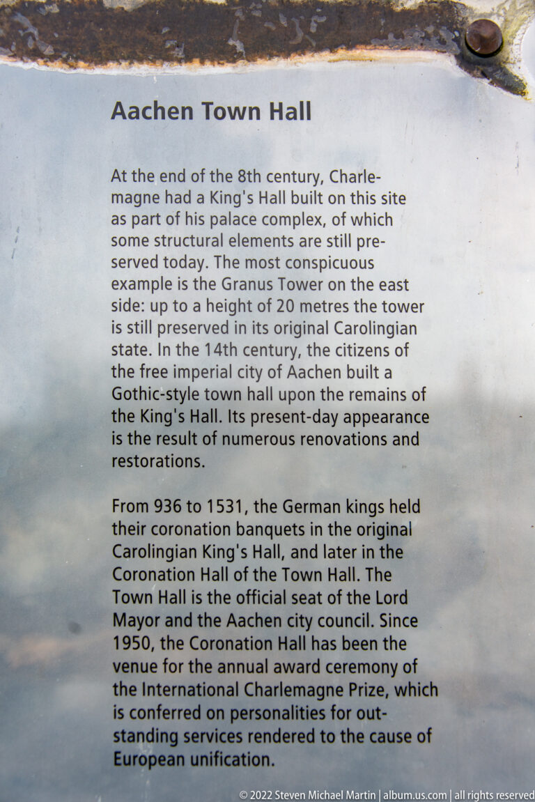 English-language information panel describing the history, coronation banquets, fires, restorations, and civic role of Aachen Town Hall.
