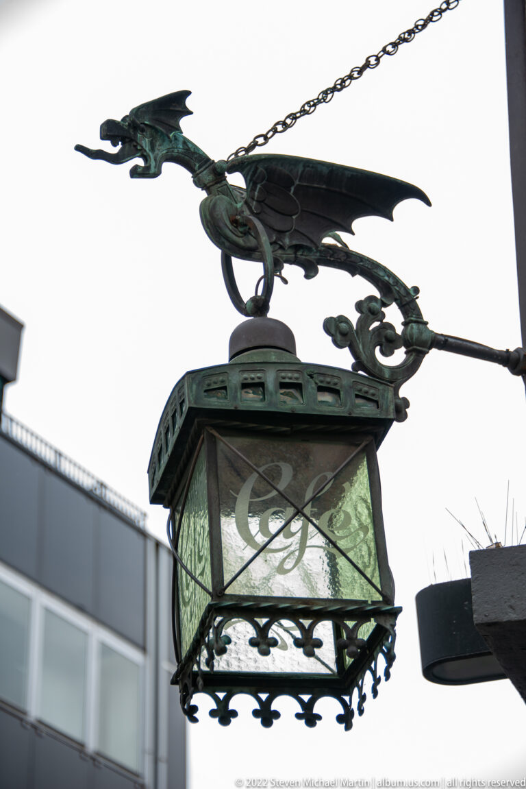 Decorative hanging lantern topped by a metal dragon with spread wings and long tail.