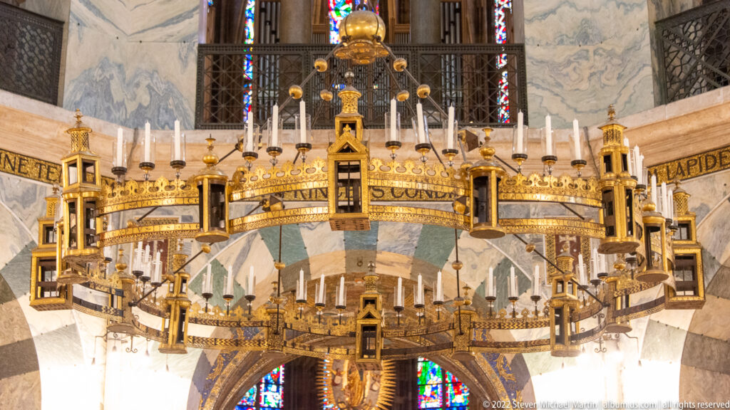 Gilded circular Barbarossa Chandelier suspended inside Aachen Cathedral, with tower-like elements and candle fittings.