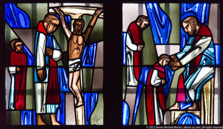 Modern stained glass showing the Crucifixion and adjacent Passion scenes in red, blue, white, and green.