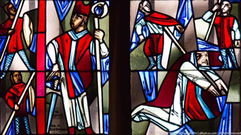 Modern stained glass with a mitred bishop holding a crozier beside other robed ecclesiastical figures.