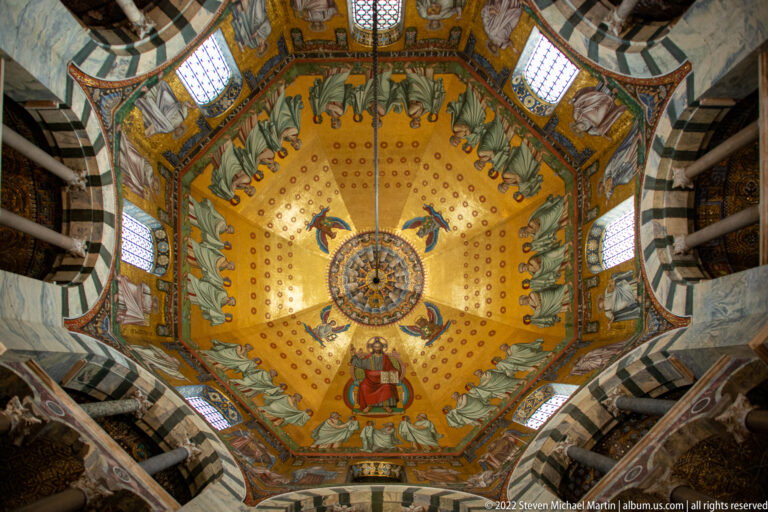 Upward view of an octagonal gold mosaic vault with central medallion, enthroned figure, and encircling standing figures.