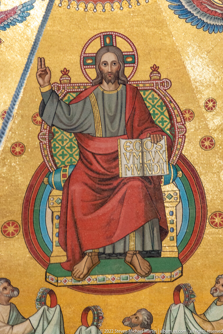 Enthroned Christ on a gold mosaic ground, blessing with one hand and holding an open book.