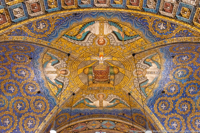Blue-and-gold mosaic vault with central throne motif, winged figures, and dense scrolling ornament.