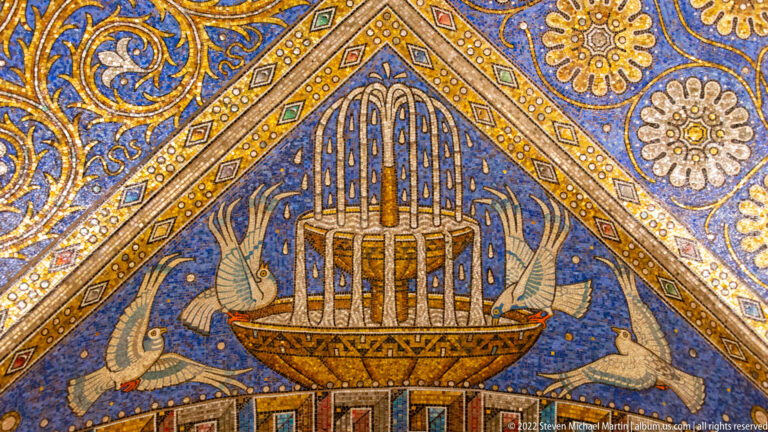 Ark-like boat with tall barred structure, flanked by birds in a blue-and-gold triangular mosaic panel.