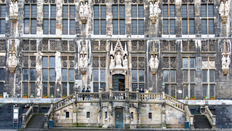 Centered view of Aachen Town Hall entrance stair beneath rows of tall windows and sculptural niches.