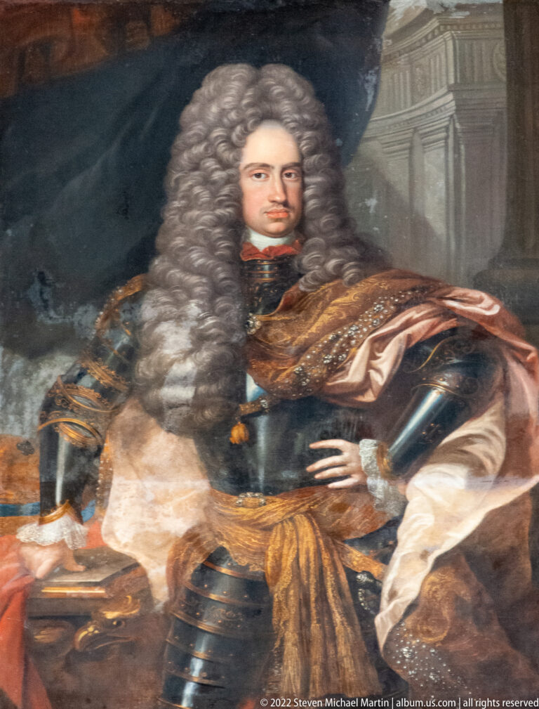 Formal painted portrait of a long-haired nobleman in armor with a draped mantle and architectural background.