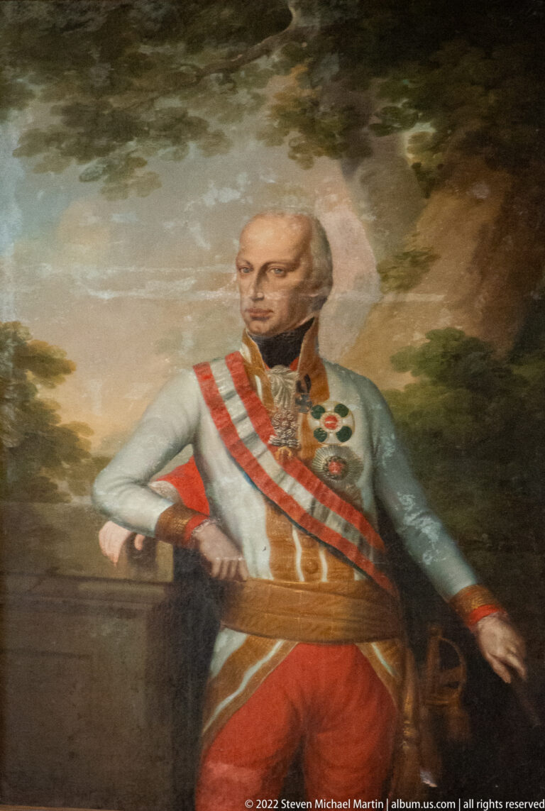 Full-length painted portrait of a decorated officer in a white uniform with red sash and medals.