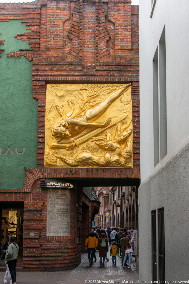 Entrance to Böttcherstraße with the large gilded Der Lichtbringer relief mounted above a narrow pedestrian passage.