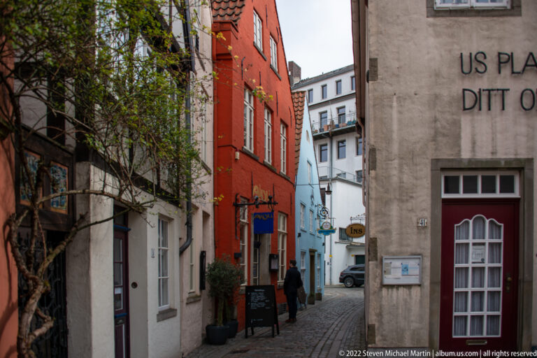 Narrow pedestrian alley in Bremen’s Schnoor Quarter lined with colorful closely spaced historic houses and small shop signs.