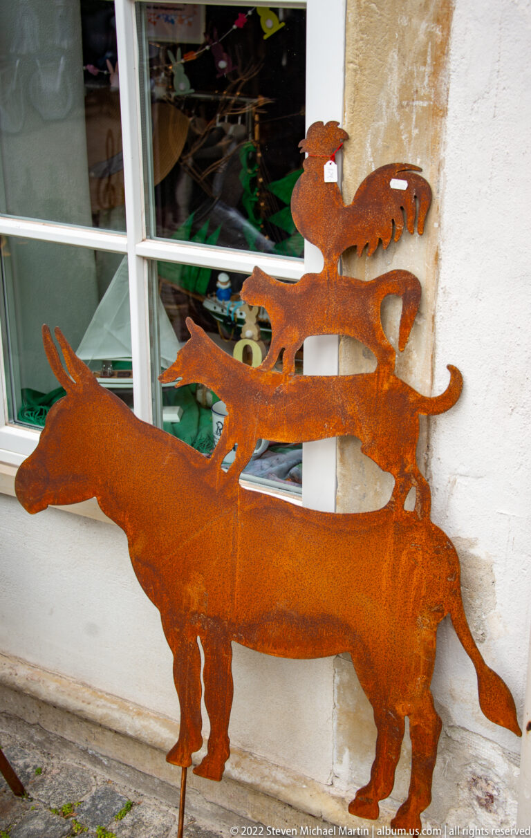 Rust-colored metal silhouette of donkey, dog, cat, and rooster stacked as the Bremen Town Musicians.