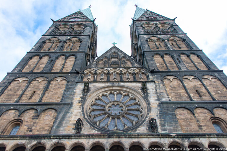Low-angle view of Bremen Cathedral’s twin towers, central rose window, and green copper roofs.