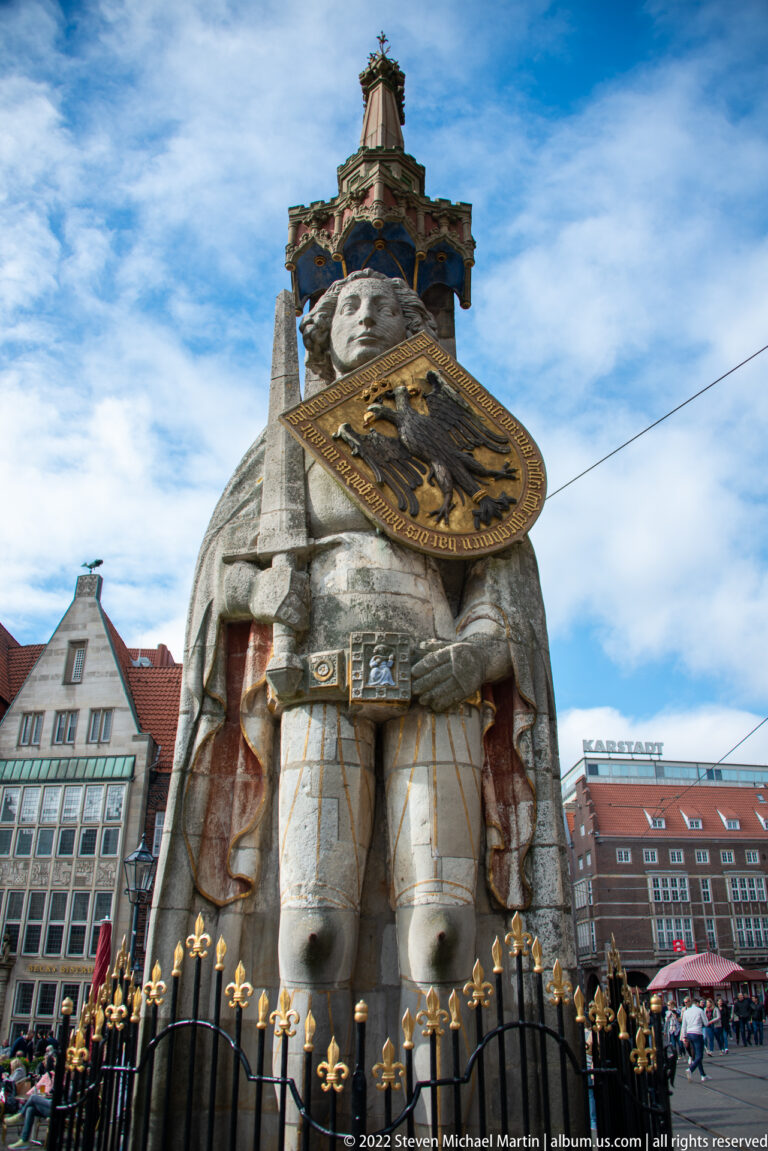 Low-angle full view of the Bremen Roland statue holding the imperial eagle shield beneath an ornate canopy.