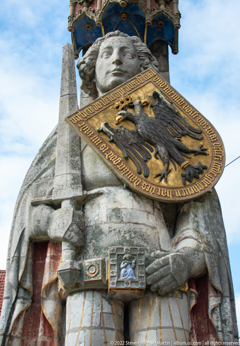 Close low-angle detail of Bremen Roland holding the imperial eagle shield and sword beneath the canopy.